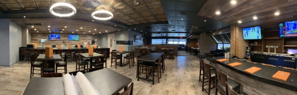 Sushi restaurant with black tables, TV's mounted on wall, and circle lighting fixtures