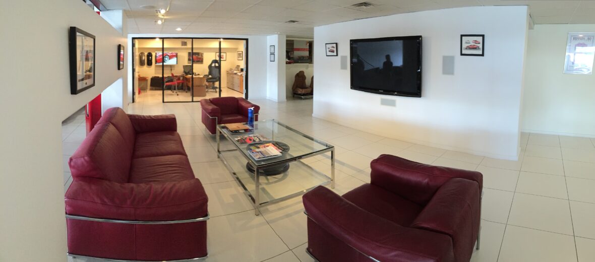 Waiting Area with red couches, glass table and mounted tv on opposite white walls