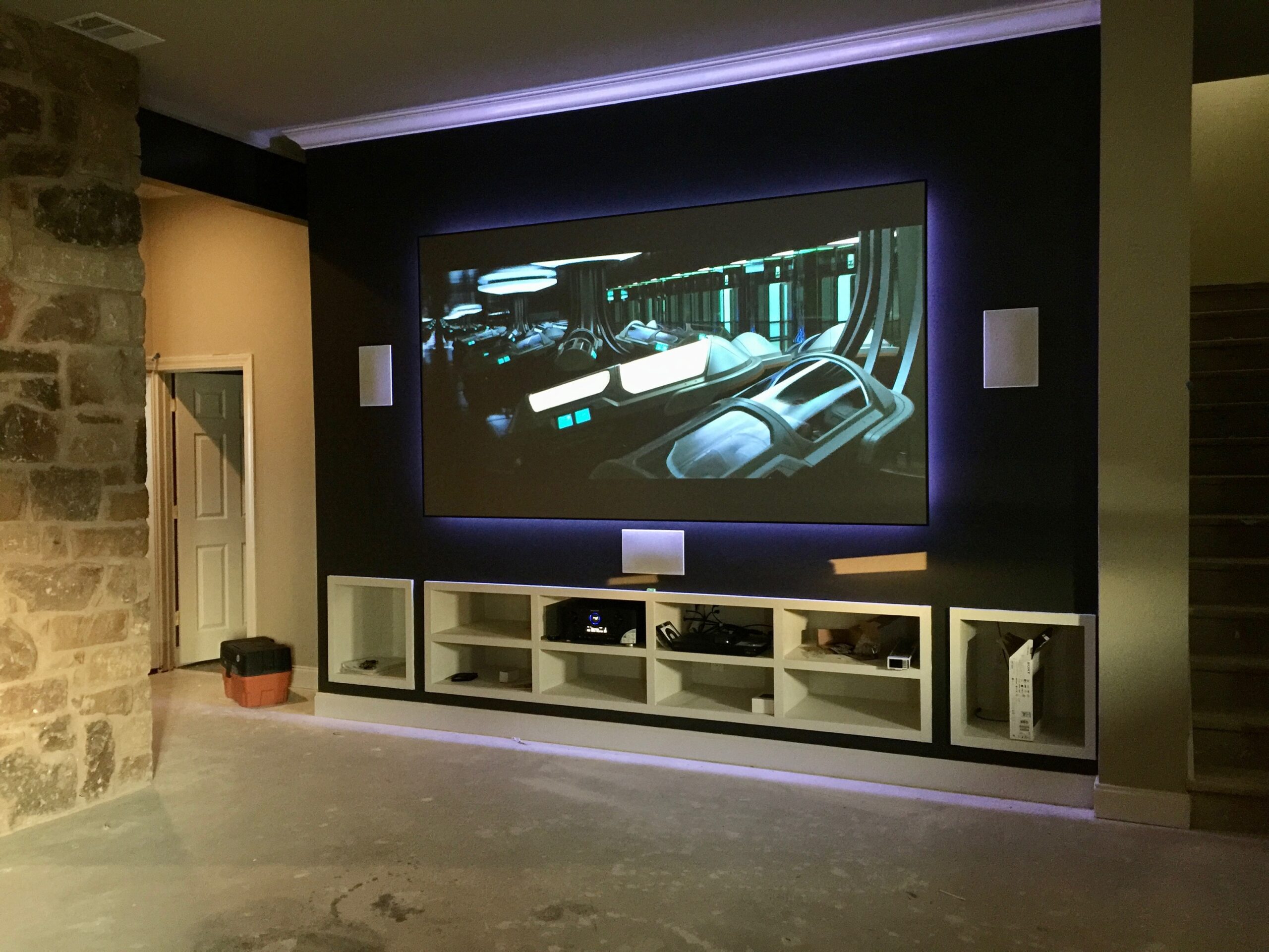Home theater room with short throw laser projection, hidden pristine sound system and custom theater lighting