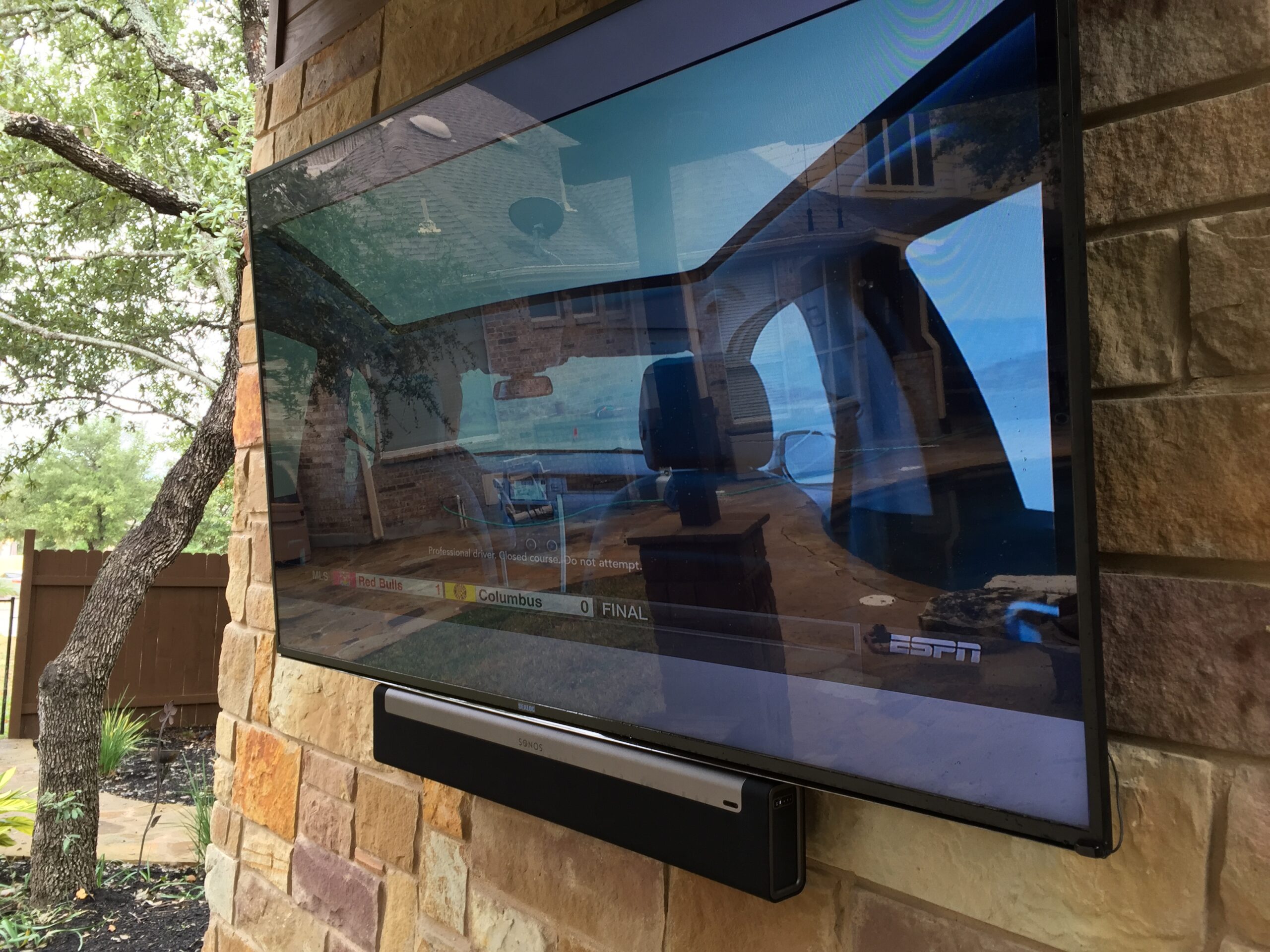 Outdoor weatherproof TV mounted on brick wall